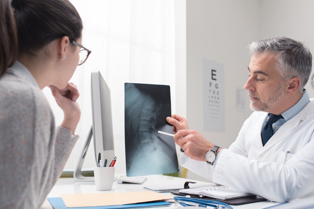 Médico del dolor mostrando la radiografía al paciente