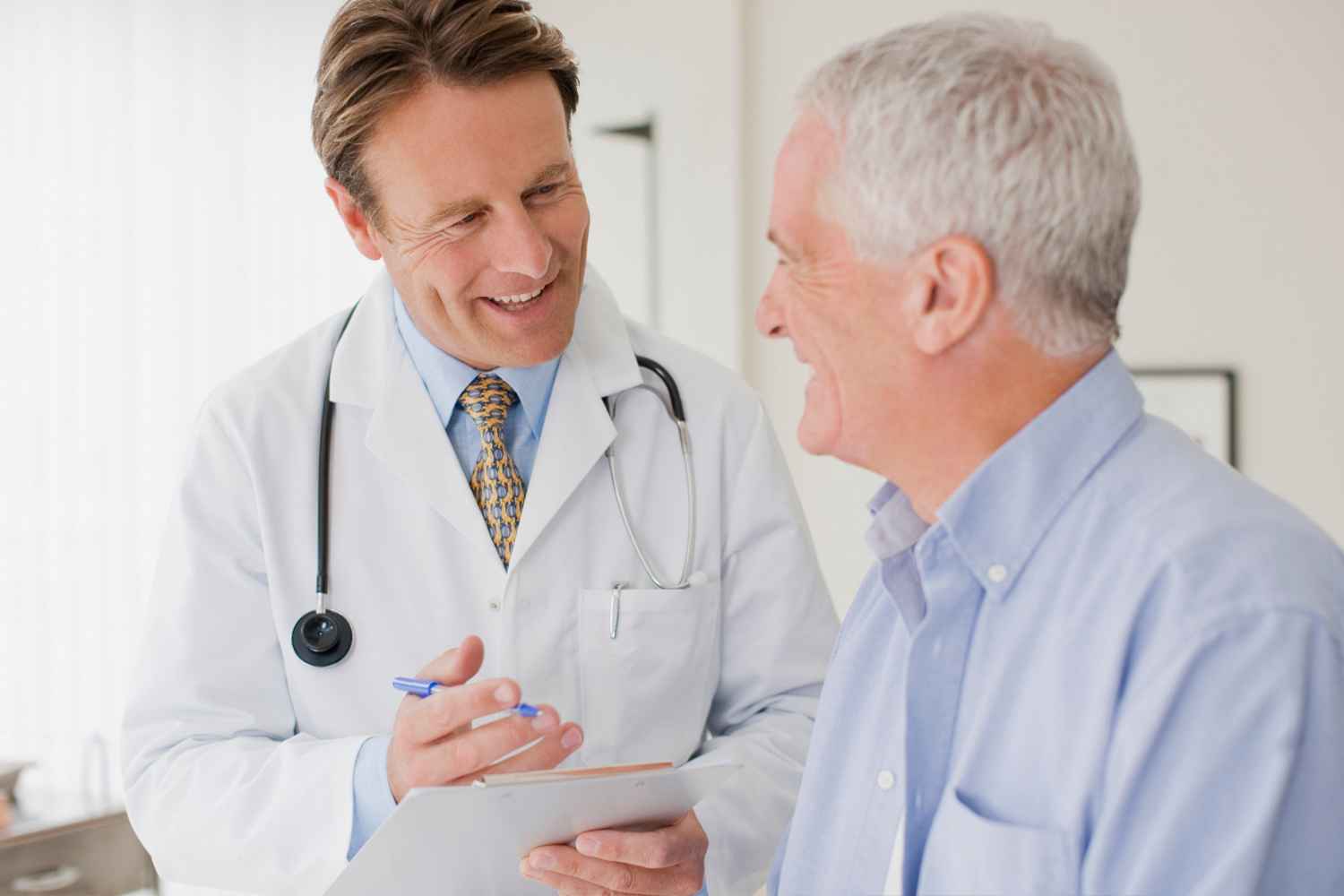 Un médico hablando con un paciente de edad avanzada durante una consulta médica.